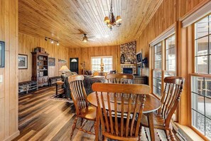 A wooden interior with a dining area, bookshelves, and a fireplace.