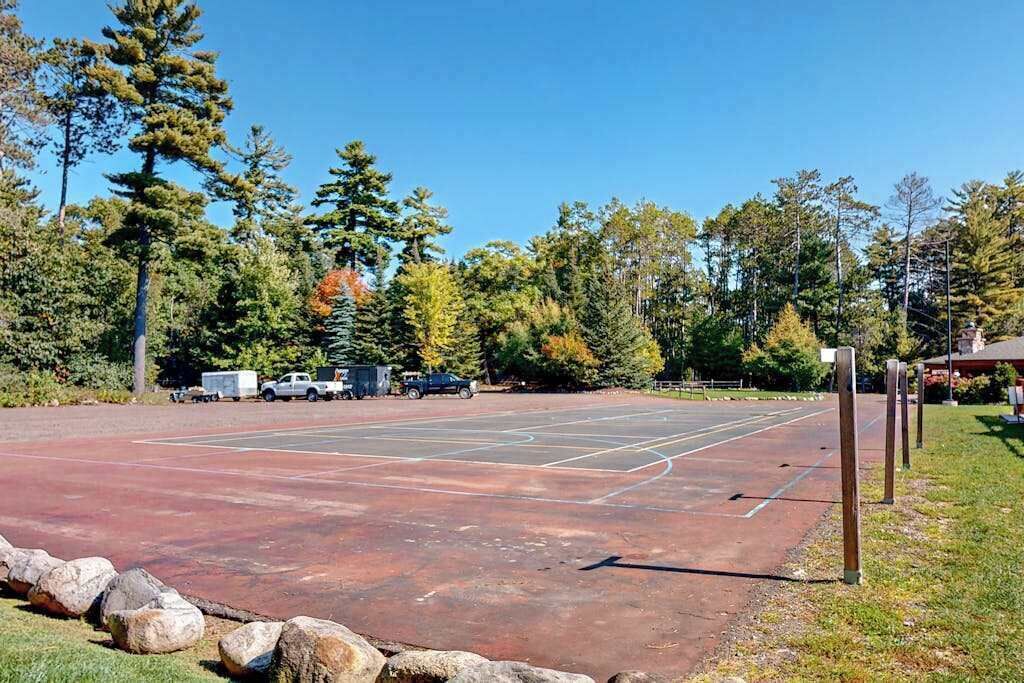 An outdoor basketball court surrounded by trees and rocks.