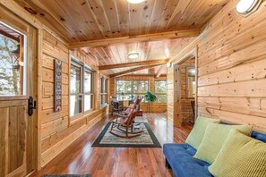 A wooden cabin interior with a sofa, rocking chair, and a dining area. - History-filled lakefront home with dock, fire pit, fireplace, & kayaks - dogs OK (Mercer)