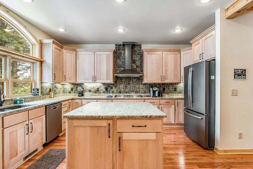 A kitchen with wooden cabinets, a central island, a built-in stove, and a refrigerator.