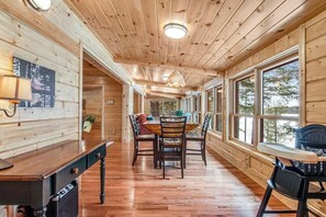 A wooden cabin interior with a dining area, large windows, and a wooden ceiling. - History-filled lakefront home with dock, fire pit, fireplace, & kayaks - dogs OK (Mercer)