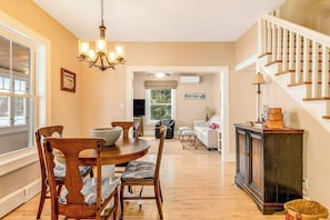 A dining area with a wooden table and chairs, a chandelier, and a staircase.