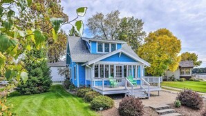 A blue house with a covered porch and a lawn. - Charming lakefront home with shared dock, porch, & sunroom - walk downtown (Minocqua)