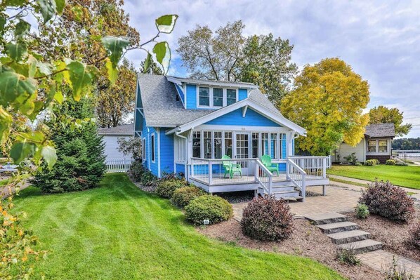 A blue house with a covered porch and a lawn.