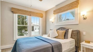 A bedroom with a bed, two windows with blinds, a ceiling fan, and a nightstand. - Charming lakefront home with shared dock, porch, & sunroom - walk downtown (Minocqua)