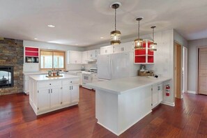 A spacious kitchen with white cabinetry, a large island, and pendant lighting.