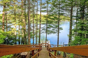 A wooden bridge leading to a lake surrounded by tall trees. - Lakefront dog-friendly gem with private dock, wood stove, large deck & free WiFi (Mercer)
