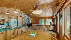 Interior de una cabaña de madera con cocina, comedor y sala de estar.