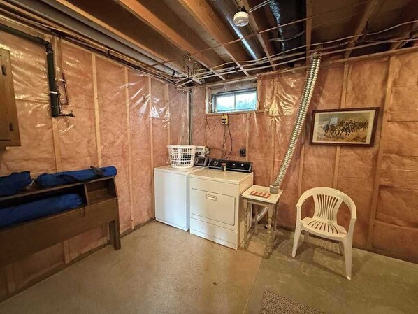 A laundry room with a washing machine, dryer, and ironing station. - Cozy, Peaceful, Lakefront Retreat with Private Walking trails, Fire pit, & More (Eagle River)
