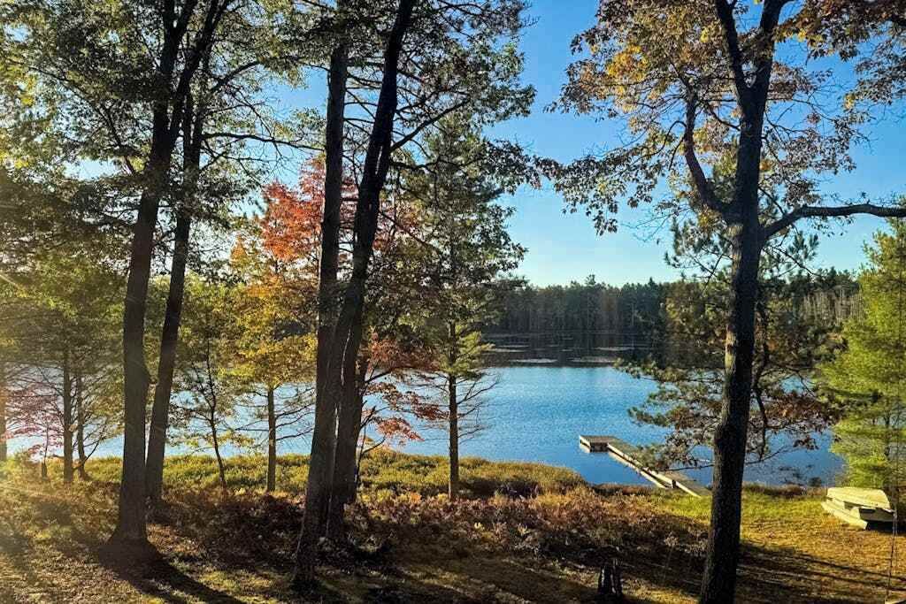 Metsäinen alue, jossa on järvi, puinen laituri ja penkki.