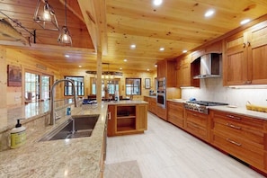 Una cocina amplia con gabinetes de madera, una isla central, electrodomésticos de acero inoxidable y encimera de granito.