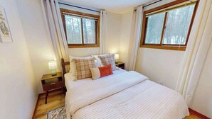 Een slaapkamer met een groot bed, twee nachtkastjes, een raam en een deur.