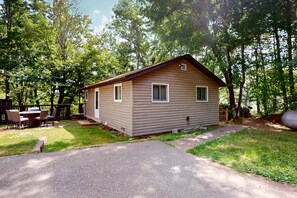 Une cabane de plain-pied avec une porte d’entrée, deux fenêtres et un petit porche.