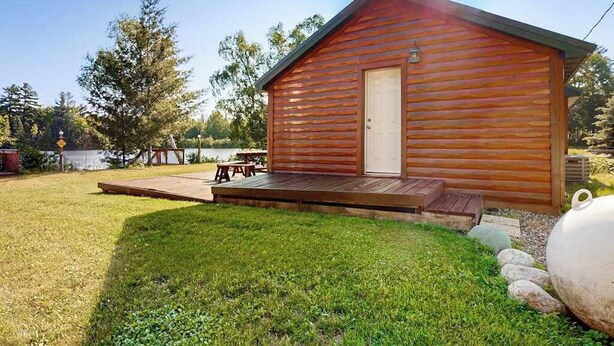 A small wooden cabin with a deck, a door, and a window. - Cozy Cabin located on the Turtle Flambeau Flowage, great for all seasons! (Mercer)