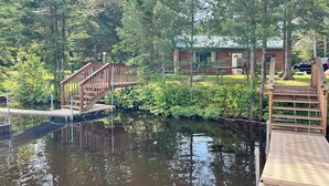 A wooden dock leading to a cabin surrounded by dense forest. - Cozy Cabin located on the Turtle Flambeau Flowage, great for all seasons! (Mercer)