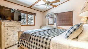 Ein Schlafzimmer mit Bett, Kommode, Schminktisch und Deckenventilator.