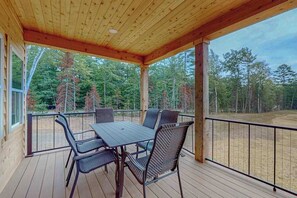 A covered outdoor area with a table and chairs, surrounded by a wooden deck and a metal railing. - Modern Northwoods Townhouse near lakes, trails & town‚Äîperfect for adventures! (Eagle River)