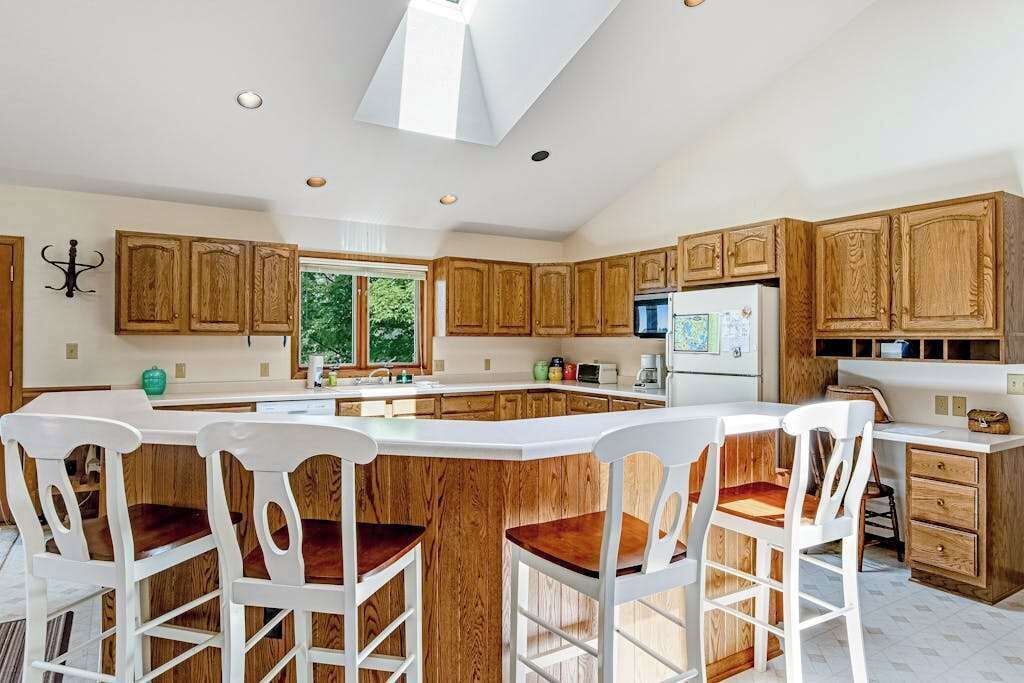 A kitchen with wooden cabinets, a central island with bar stools, and a skylight.