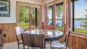 Uma mesa redonda com cadeiras em um quarto com grandes janelas com vista para um lago.