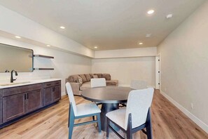 A modern kitchen with dark cabinets, a large island, and a round dining table with four chairs.
