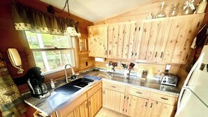 A kitchen with wooden cabinets, a sink, a coffee maker, and a toaster. - Lakefront home with, dock, grill, sunporch, WIFI, W/D near Downtown (Eagle River)
