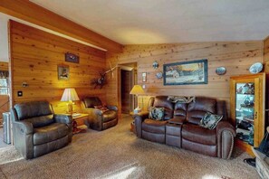Una sala de estar acogedora con paredes de madera, sofás de cuero y una chimenea.