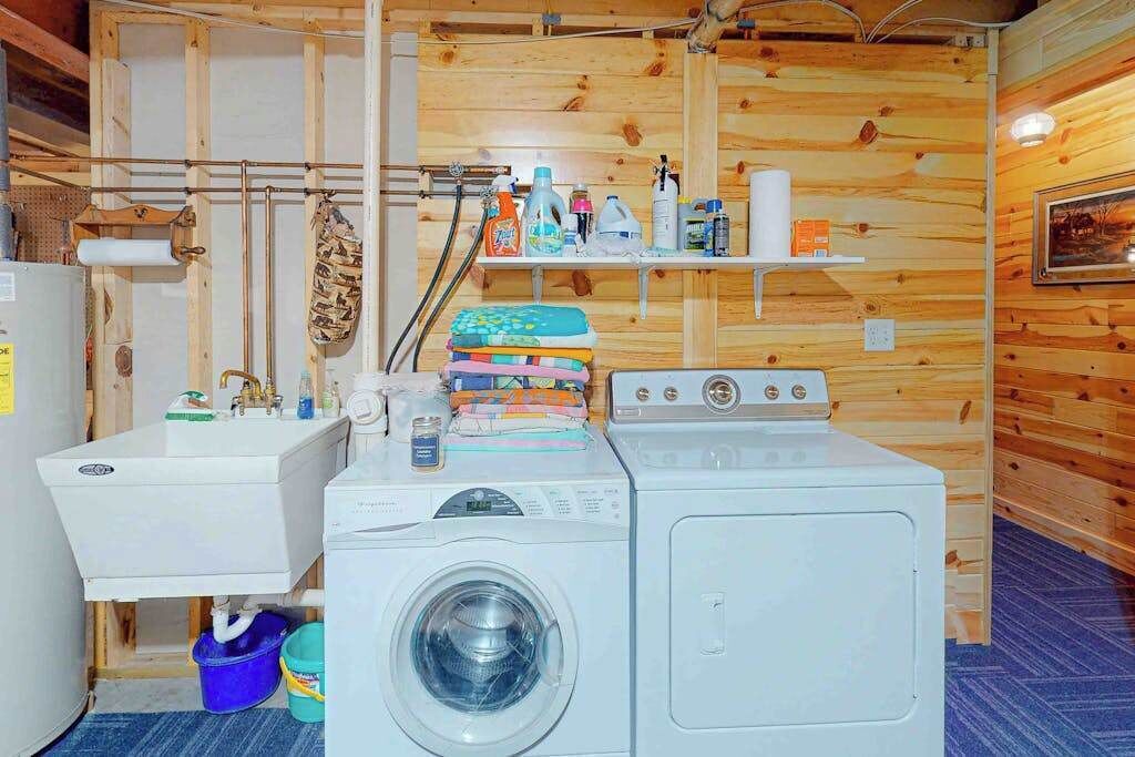 Un'area lavanderia con lavatrice, lavandino e scaffali con prodotti per la pulizia.