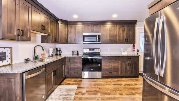 Eine moderne Küche mit Holzausstattung, Edelstahlgeräten und einer Granitarbeitsplatte.