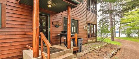 Une cabane en bois avec une véranda, des marches et un barbecue à l’extérieur.