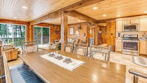 Un intérieur en bois comprenant un coin repas, une cuisine et de grandes fenêtres.