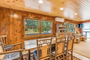 Une pièce aux murs lambrés, comprenant une table à manger et des chaises, une bibliothèque et un téléviseur.