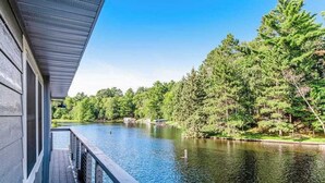 Une terrasse en bois surplombe un lac paisible, avec une forêt dense en arrière-plan.