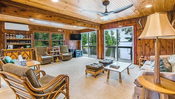 Un intérieur en bois avec un canapé, des fauteuils, une table et un téléviseur.