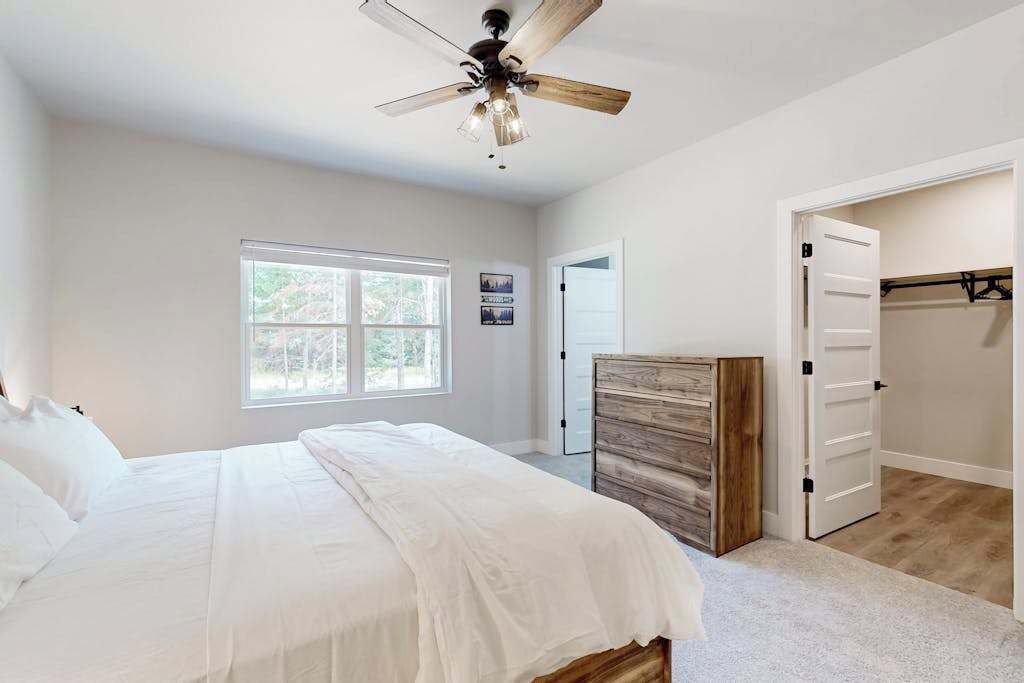 Ein Schlafzimmer mit Bett, Deckenventilator, Fenster und Kleiderschrank.