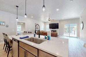 A modern kitchen with a large island, built-in appliances, pendant lighting, and a view to a living area. - Modern Northwoods Townhouse near lakes, trails & town‚ perfect for adventures! (Eagle River)