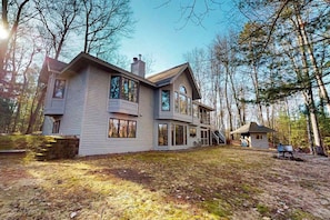 A large, modern house with multiple levels, large windows, and a stone foundation.