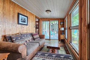 Una habitación con paneles de madera, un sofá, una mesa de centro y un ventanal grande.