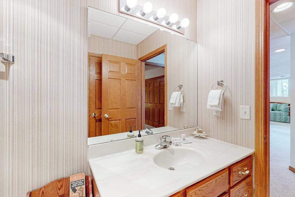 Un baño con un espejo grande, tocador y armarios de madera.