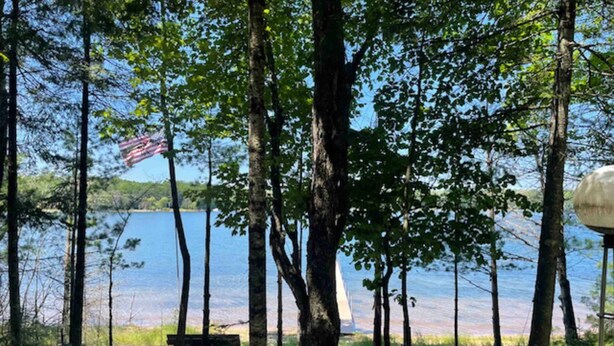 Un paisaje con un lago, árboles, un banco y una bandera estadounidense.
