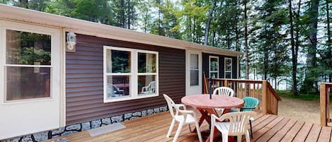 Una cabaña con terraza, mobiliario exterior y vistas al bosque circundante.