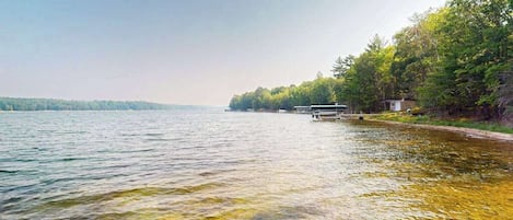 A lake with a dock and a small building on the shore.