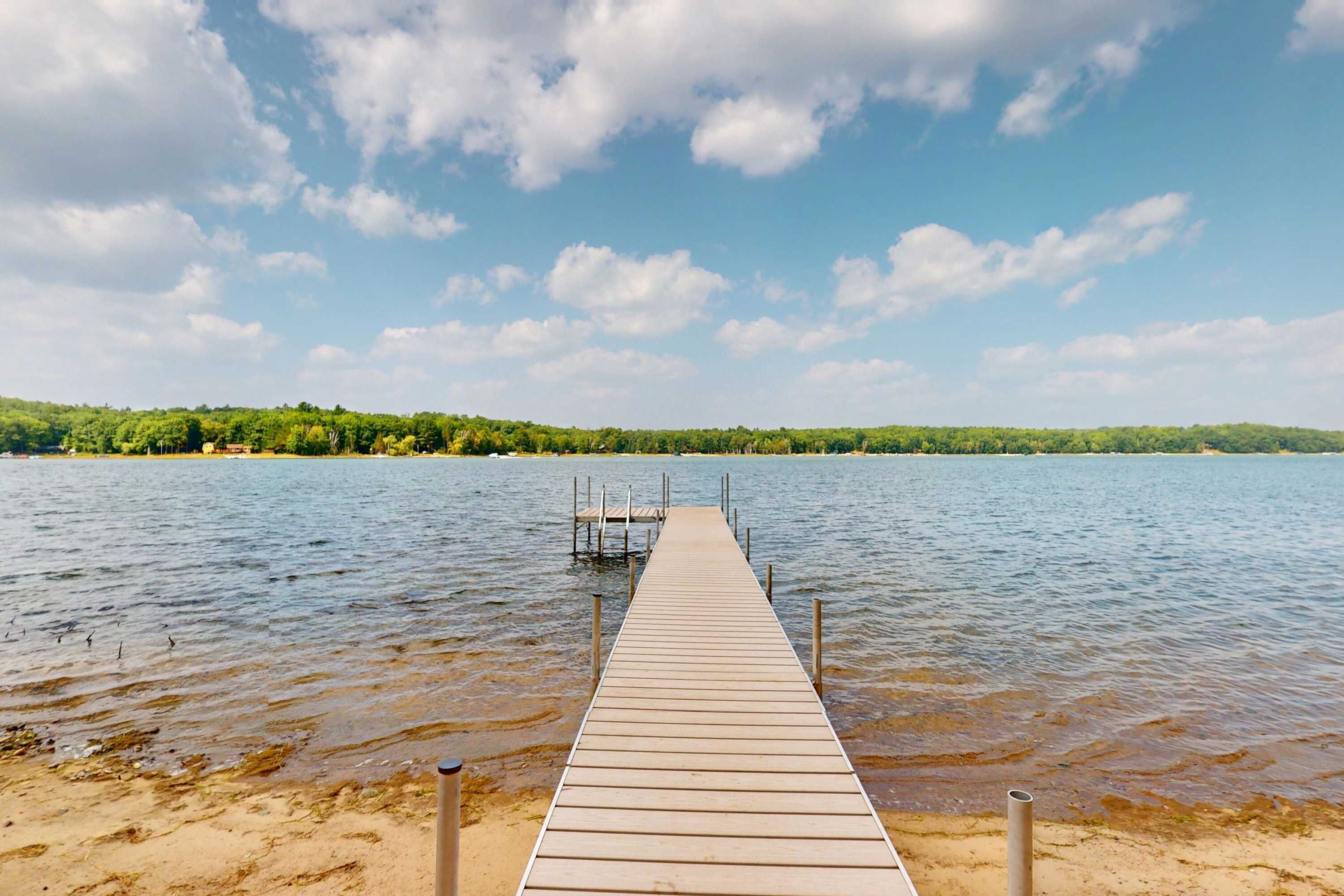 A wooden pier extending into calm water with a clear sky above.