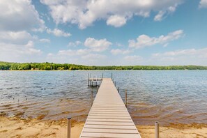 Une jetée en bois s’étendant sur une étendue d’eau calme, sous un ciel dégagé.