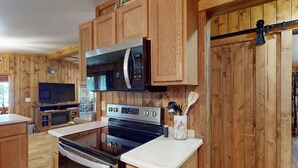 Una cocina con muebles de madera, microondas, horno y cafetera.