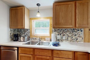 A kitchen with wooden cabinets, a double sink, a toaster, and a coffee maker.