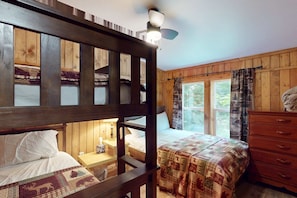 Una habitación con cama, escritorio, cómoda y ventana con cortinas.