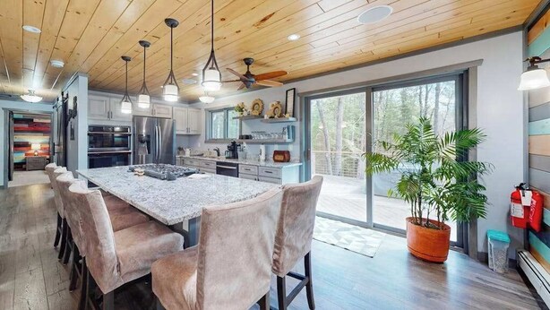A modern kitchen with a large island, pendant lights, and a view of the outdoors. - Cozy Wooded home with WIFI, Gas Grill, Two Kitchens, Near Lakes & Trails (Eagle River)