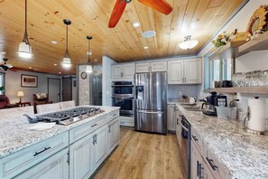 Una cocina moderna con encimeras de granito, electrodomésticos de acero inoxidable y vigas de madera en el techo.