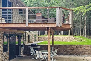 Una terraza con mobiliario exterior, una parrilla y un muro de piedra.