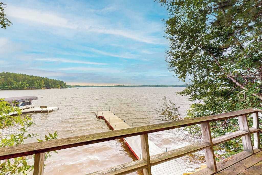 A wooden dock extending into a river with a clear view of the opposite bank.